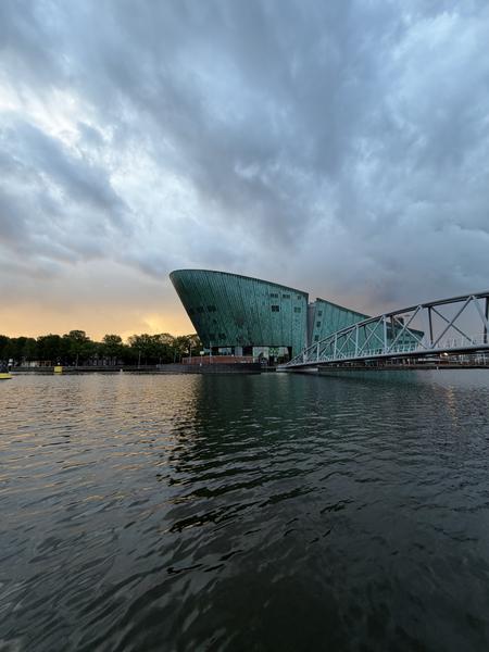 This photo captures a striking modern building with a distinctive teal facade, resembling a ship, situated by the water at Mr